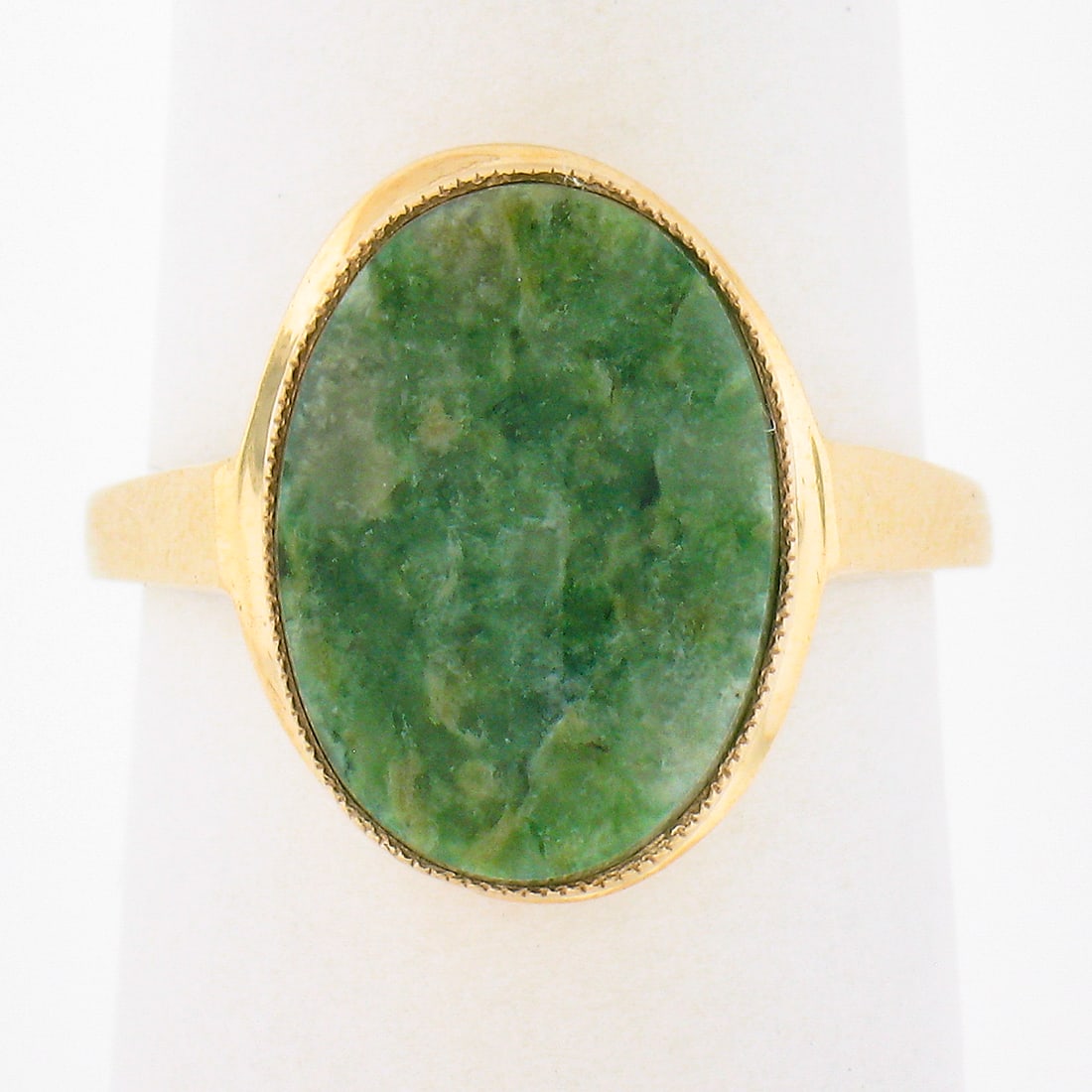 10K Yellow Gold Milgrain Bezel Oval Cabochon Jade Solitaire Ring: 10K Yellow Gold Milgrain Bezel Oval Cabochon Jade Solitaire Ring This stunning solitaire ring features a solid 10K yellow gold band, elegantly showcasing an oval cabochon cut natural jade at its cente