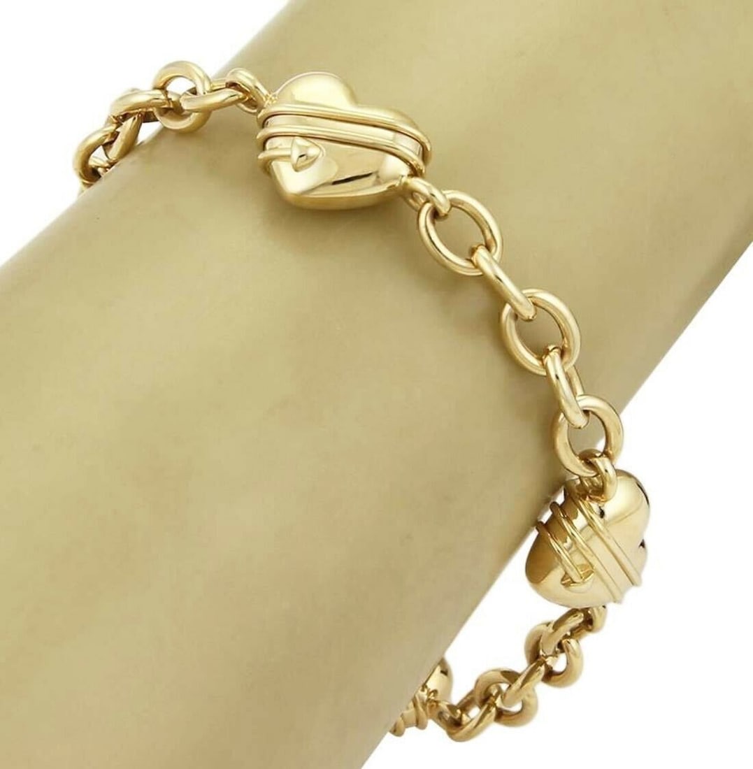 18k Yellow Gold Tiffany & Co. Cupid Heart Charm Bracelet: 18k Yellow Gold Tiffany & Co. Cupid Heart Charm Bracelet A pre-owned Tiffany & Co. bracelet crafted in solid 18k yellow gold with a chain style design. It features a cupid motif accented by four heart