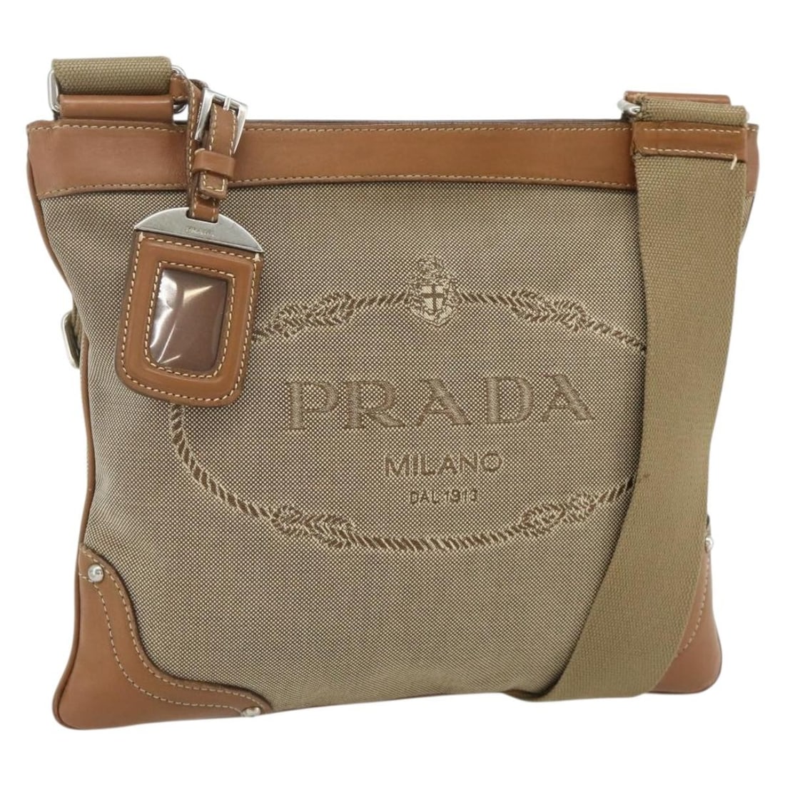 PRADA Canvas Shoulder Bag Beige Silver Name Tag Italy: PRADA Canvas Shoulder Bag Beige Silver Name Tag Italy Prada shoulder bag in beige and silver canvas, made in Italy. It comes with a name tag accessory and measures approximately 26 cm wide by 23 cm hi