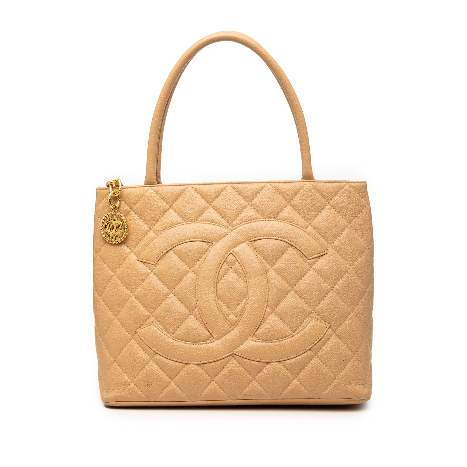 Chanel Beige Caviar Leather Medallion Tote Bag: Chanel Beige Caviar Leather Medallion Tote Bag This Chanel Caviar Medallion Tote features a quilted caviar leather body in beige, rolled leather handles, and a top zip closure. The bag includes an ext