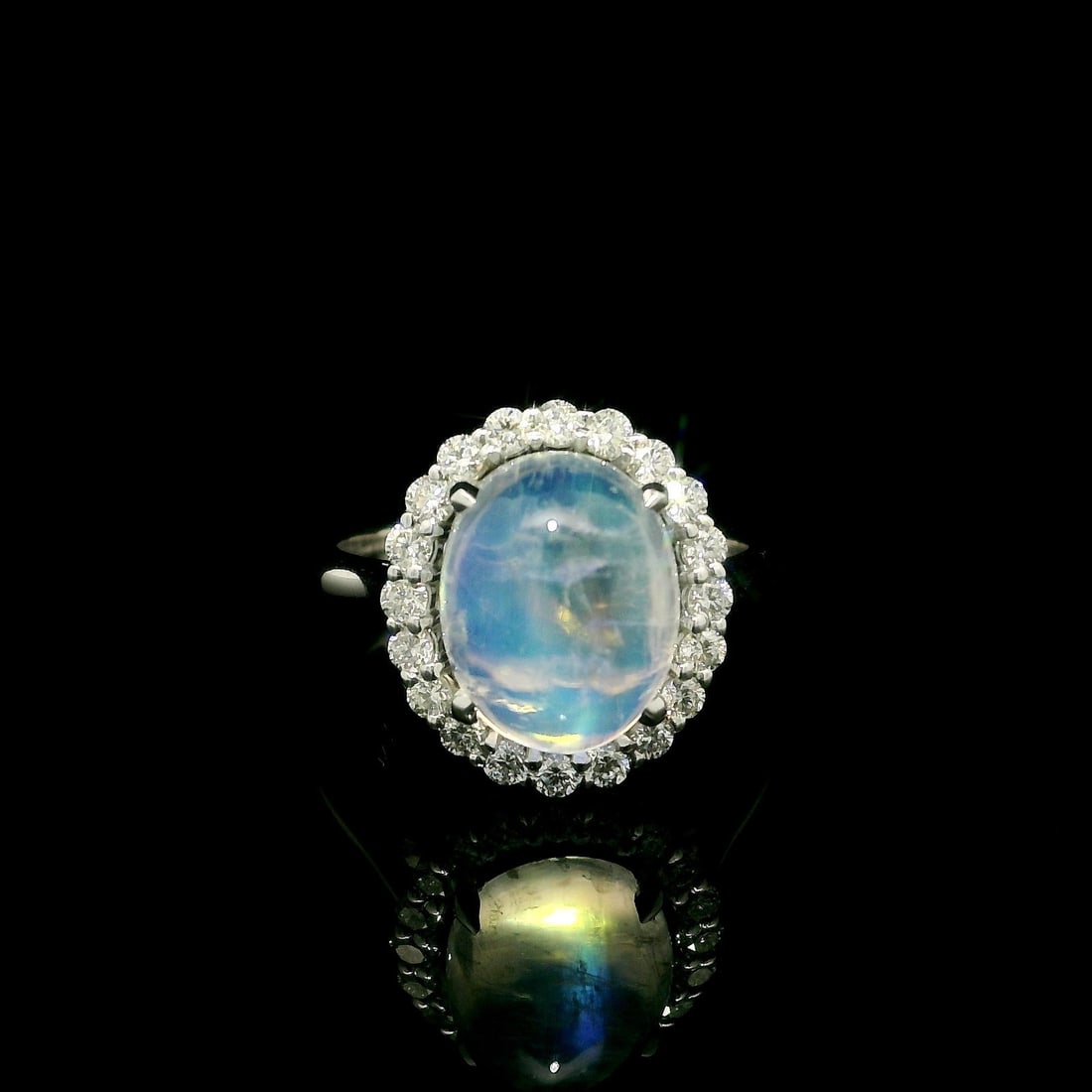 Custom 14k White Gold 4.41ct Moonstone Diamond Halo Ring: Custom 14k White Gold 4.41ct Moonstone Diamond Halo Ring This stunning halo ring features a natural blue moonstone, elegantly crafted in solid 14k white gold. The centerpiece is a prominent oval caboc