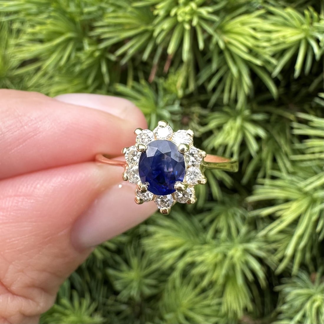 18k Gold Sapphire Floral Cluster Ring with 10 Diamonds Size 7: 18k Gold Sapphire Floral Cluster Ring with 10 Diamonds Size 7 This dainty cocktail ring features an oval brilliant cut natural sapphire with a vibrant blue hue, prong set at the center. Surrounding th