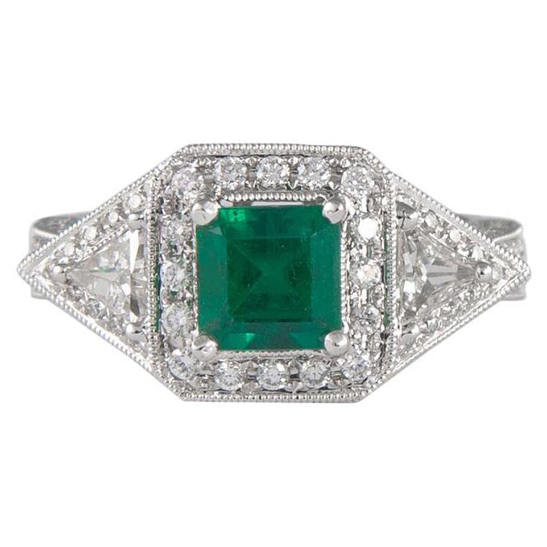 1.08 Carat Emerald Halo Ring with Diamonds in 18k White Gold: 1.08 Carat Emerald Halo Ring with Diamonds in 18k White Gold This exquisite three-stone ring features a stunning 1.08 carat emerald cut emerald at its center, surrounded by a halo of 1.03 carats of ro