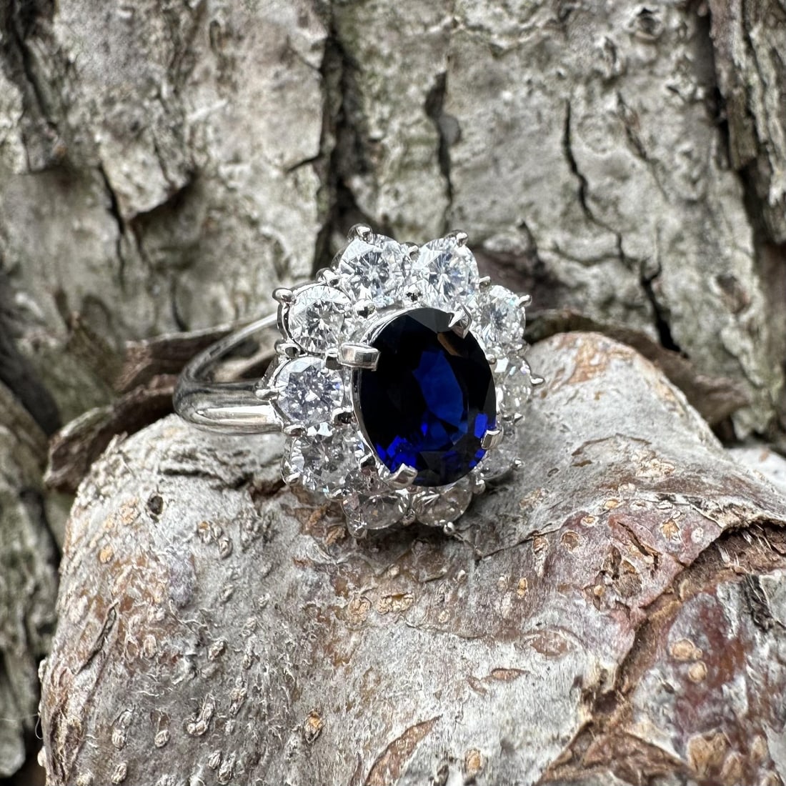 Platinum Sapphire and Diamond Halo Cocktail Ring with GIA Certificate: Platinum Sapphire and Diamond Halo Cocktail Ring with GIA Certificate This cocktail-style ring features a natural deep royal blue oval-cut sapphire weighing 1.31 carats, surrounded by a halo cluster o