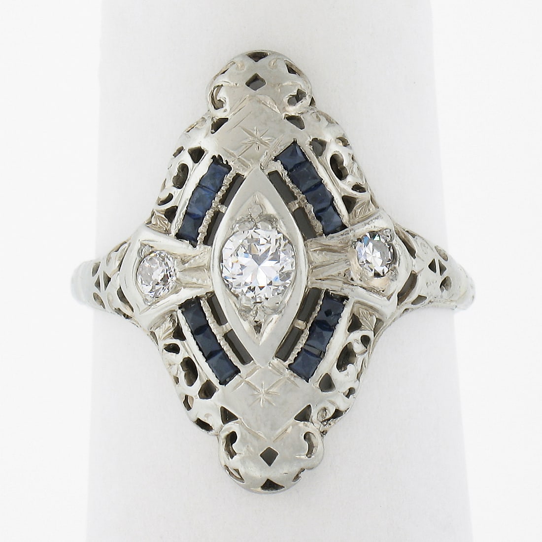 Antique Art Deco 18K Gold 0.12ctw Diamond Sapphire Filigree Navette Ring: Antique Art Deco 18K Gold 0.12ctw Diamond Sapphire Filigree Navette Ring This exquisite Antique Art Deco dinner ring features a stunning navette shape crafted from solid 18K white gold. It showcases a