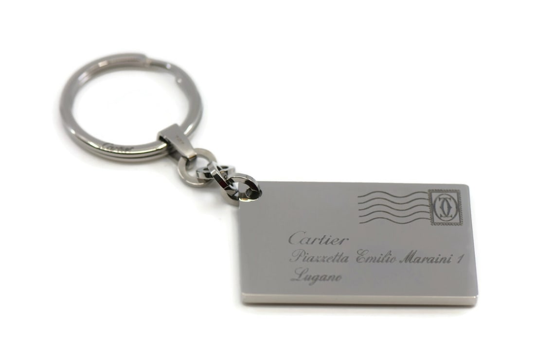 Cartier Lugano Silver Tone Stainless Steel Key Chain with Box: Cartier Lugano Silver Tone Stainless Steel Key Chain with Box This Cartier Lugano key chain is crafted from stainless steel in a sleek silver color. Designed for men, it offers a stylish and durable a
