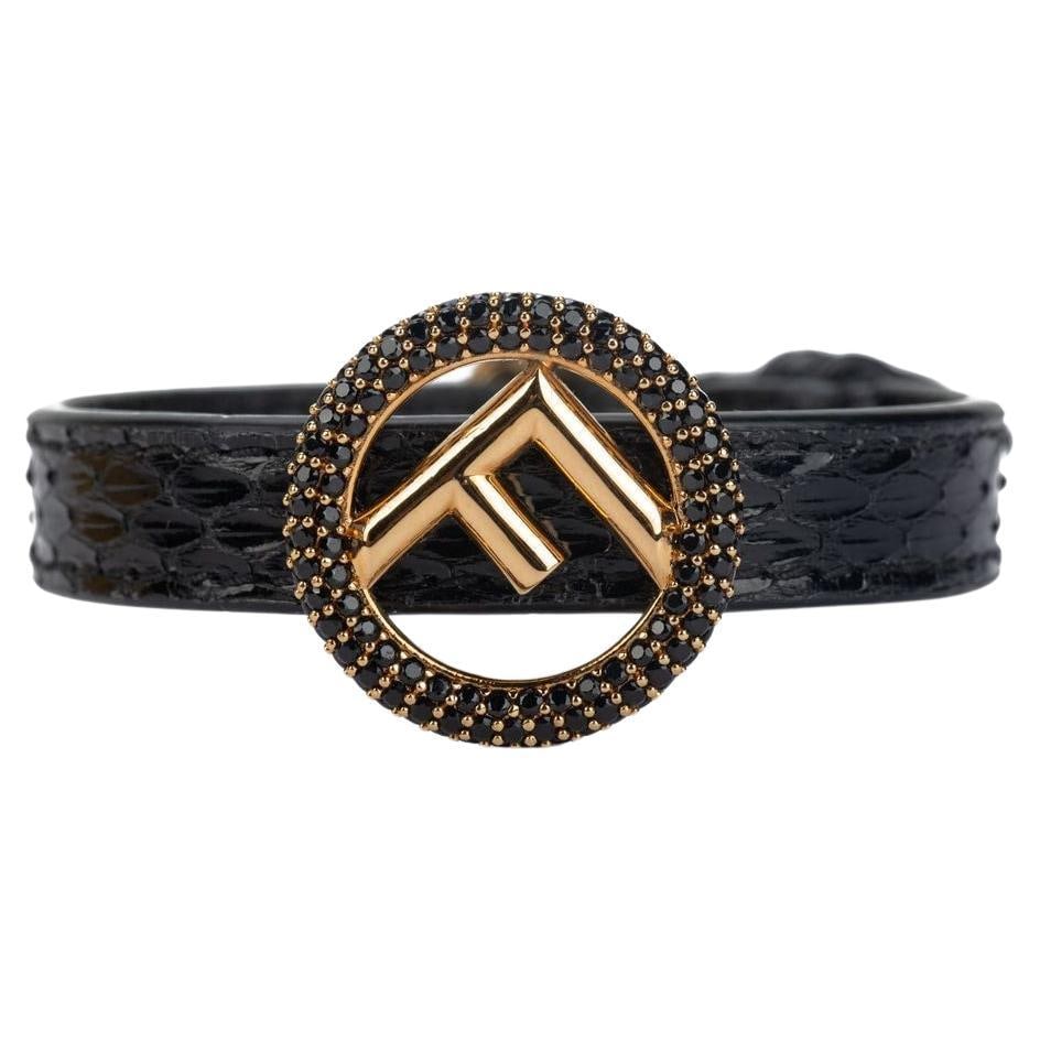 Fendi Black Lizard Leather Bracelet with Gold F Logo 2021: Fendi Black Lizard Leather Bracelet with Gold F Logo 2021 This elegant Fendi bracelet showcases a luxurious design crafted from black lizard leather. It features a striking F logo in gold, serving as 