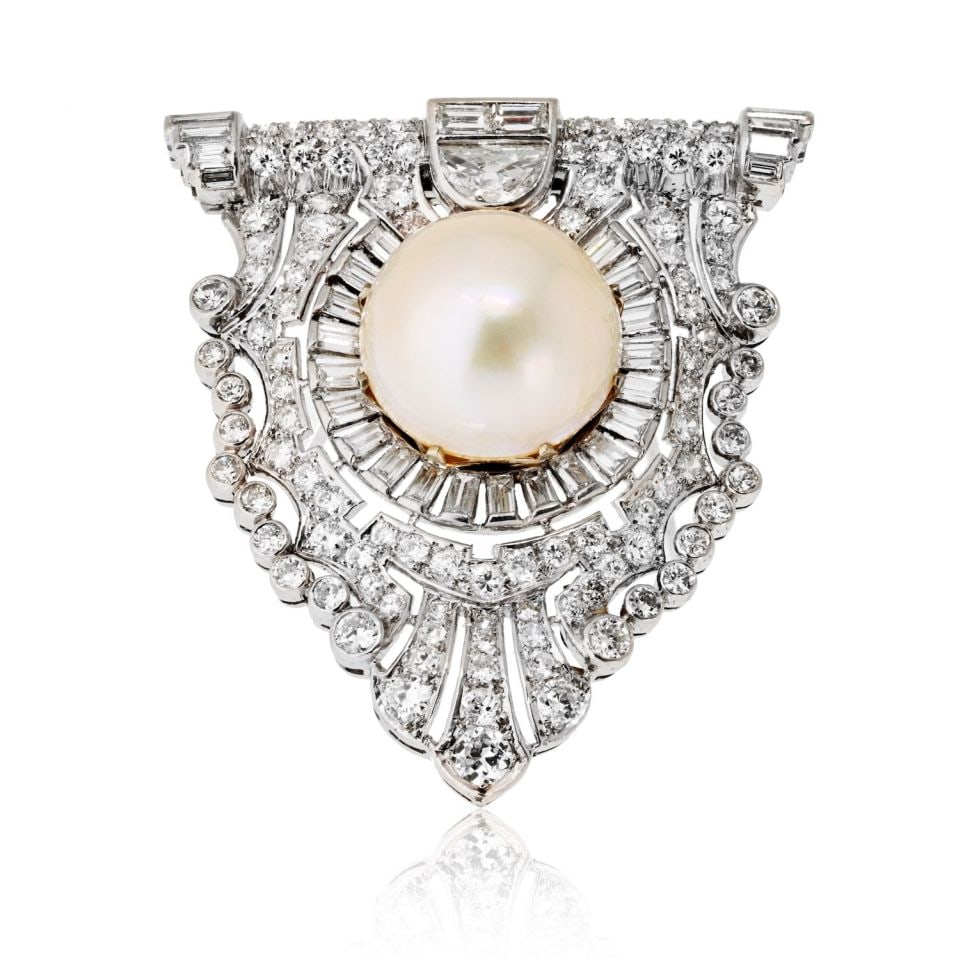 Art Deco Platinum Brooch with 10mm Pearl and 6 Carats Diamonds: Art Deco Platinum Brooch with 10mm Pearl and 6 Carats Diamonds This exquisite Art Deco platinum clip brooch is a stunning representation of 1920s and 1930s glamour. At its heart is a luminous 10mm pea