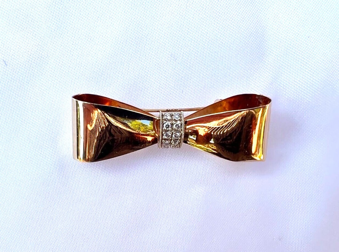 1950s French 14k Gold Bow Brooch with Diamonds: 1950s French 14k Gold Bow Brooch with Diamonds This exquisite 1950's French brooch showcases a stunning bow design crafted from 14k yellow gold. Adorned with approximately 0.15 carats of SI quality di