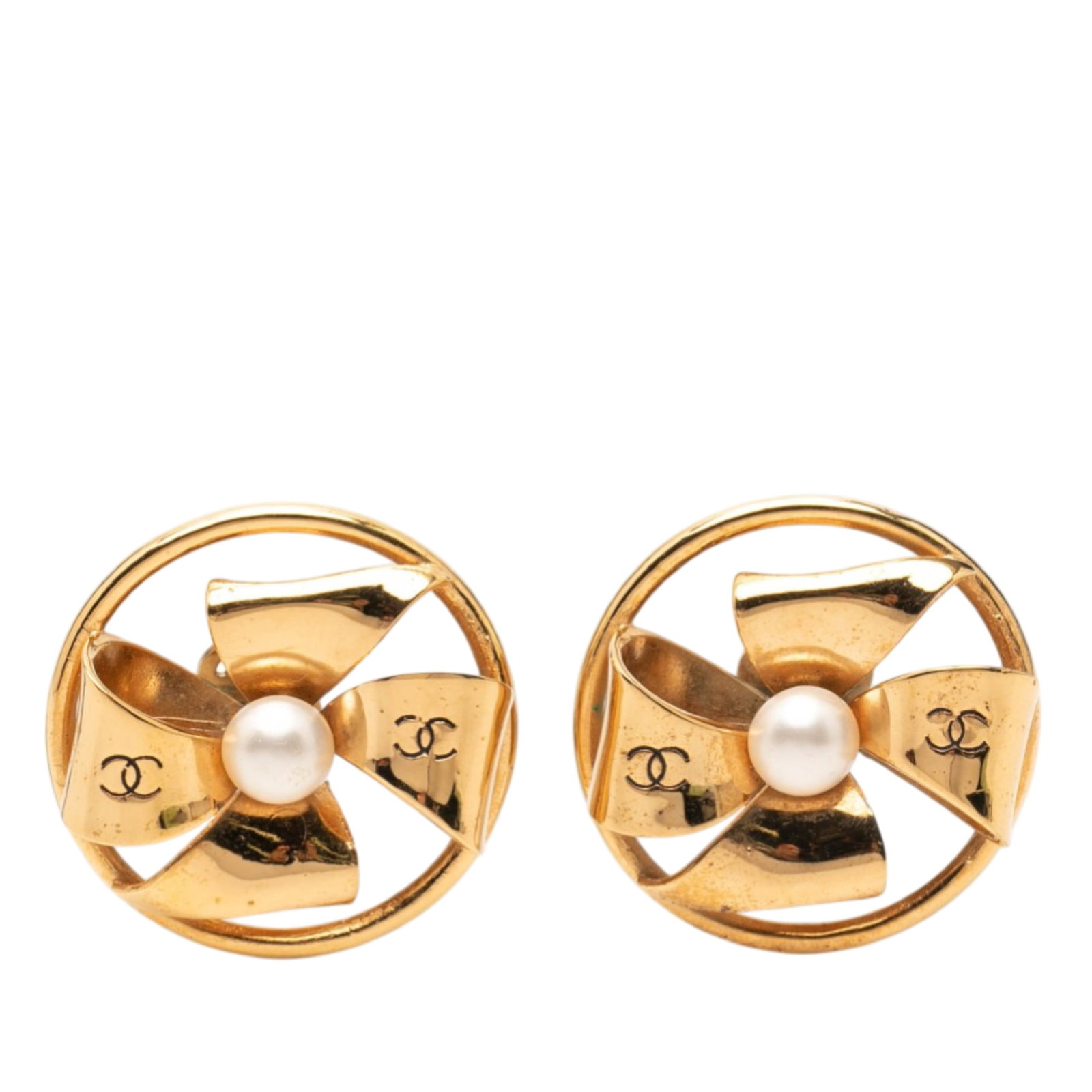 Chanel CC gold tone faux pearl pinwheel clip on earrings: Chanel CC gold tone faux pearl pinwheel clip on earrings These Chanel clip-on earrings feature a pinwheel ribbon design crafted from gold tone metal and are embellished with faux pearl accents. Made i