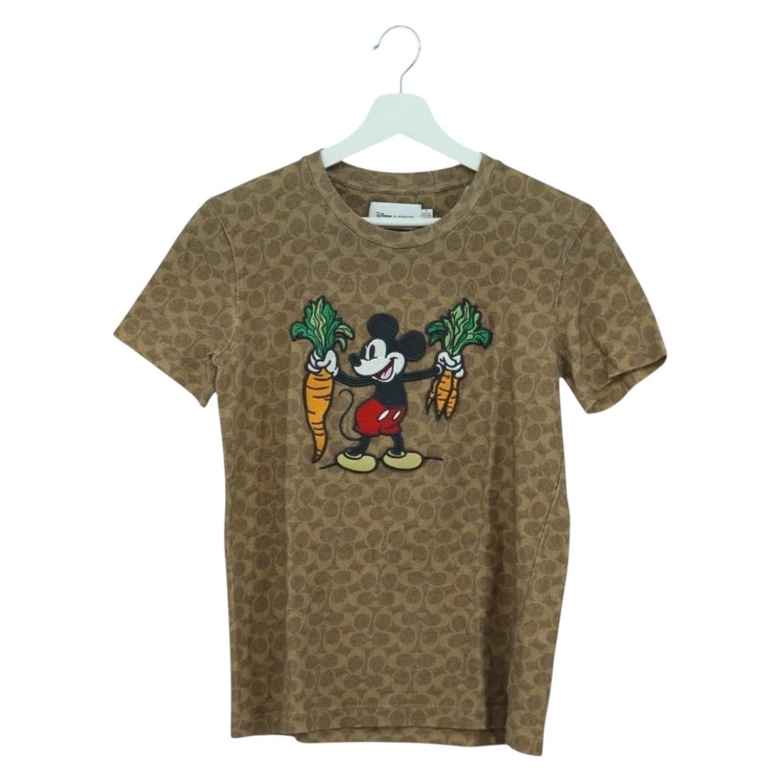 Coach Disney Brown Cotton Short Sleeve T Shirt: Coach Disney Brown Cotton Short Sleeve T Shirt A brown short-sleeved T-shirt by Coach with Disney Signature styling, made of cotton. The item is listed in pristine condition, with only slight surface