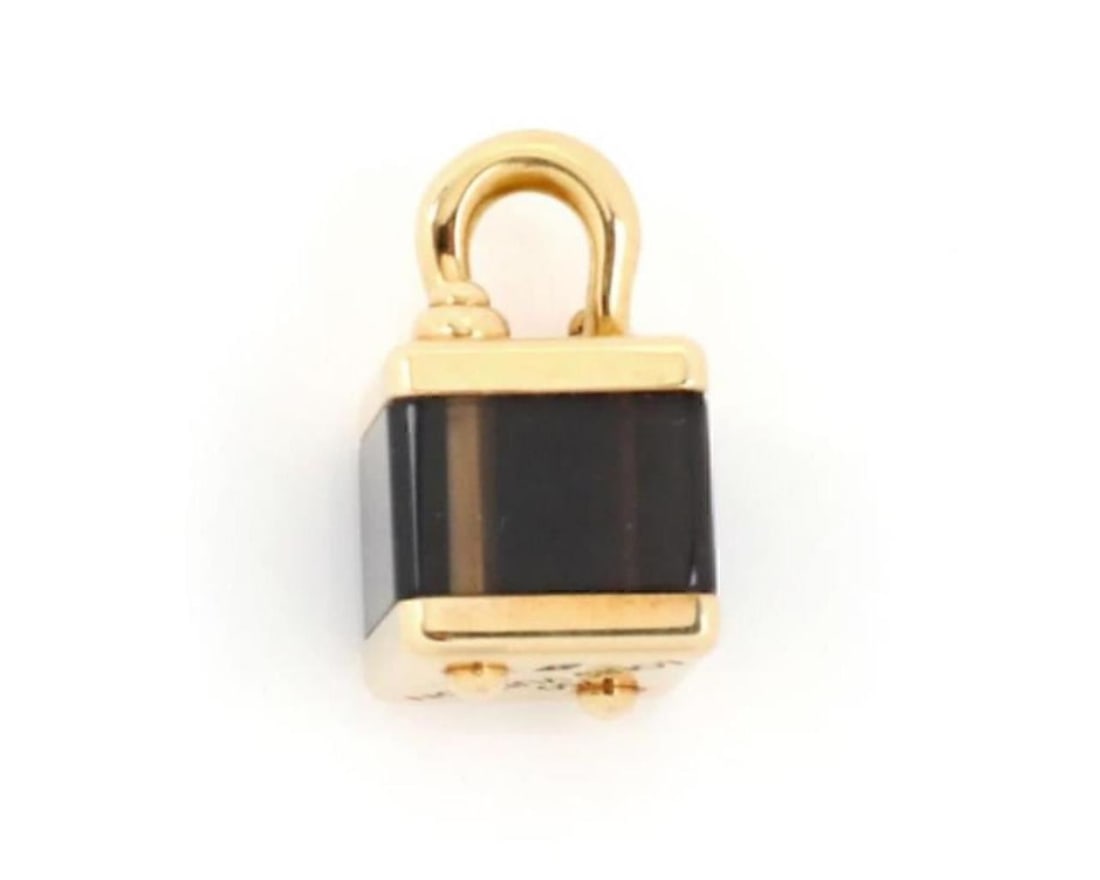 18k Yellow Gold Louis Vuitton Cube Bag Charm Pendant: 18k Yellow Gold Louis Vuitton Cube Bag Charm Pendant A pre-owned Louis Vuitton Brown Cube Bag Charm Pendant crafted in 18k yellow gold, featuring a miniature cube-shaped bag design inspired by the Mai