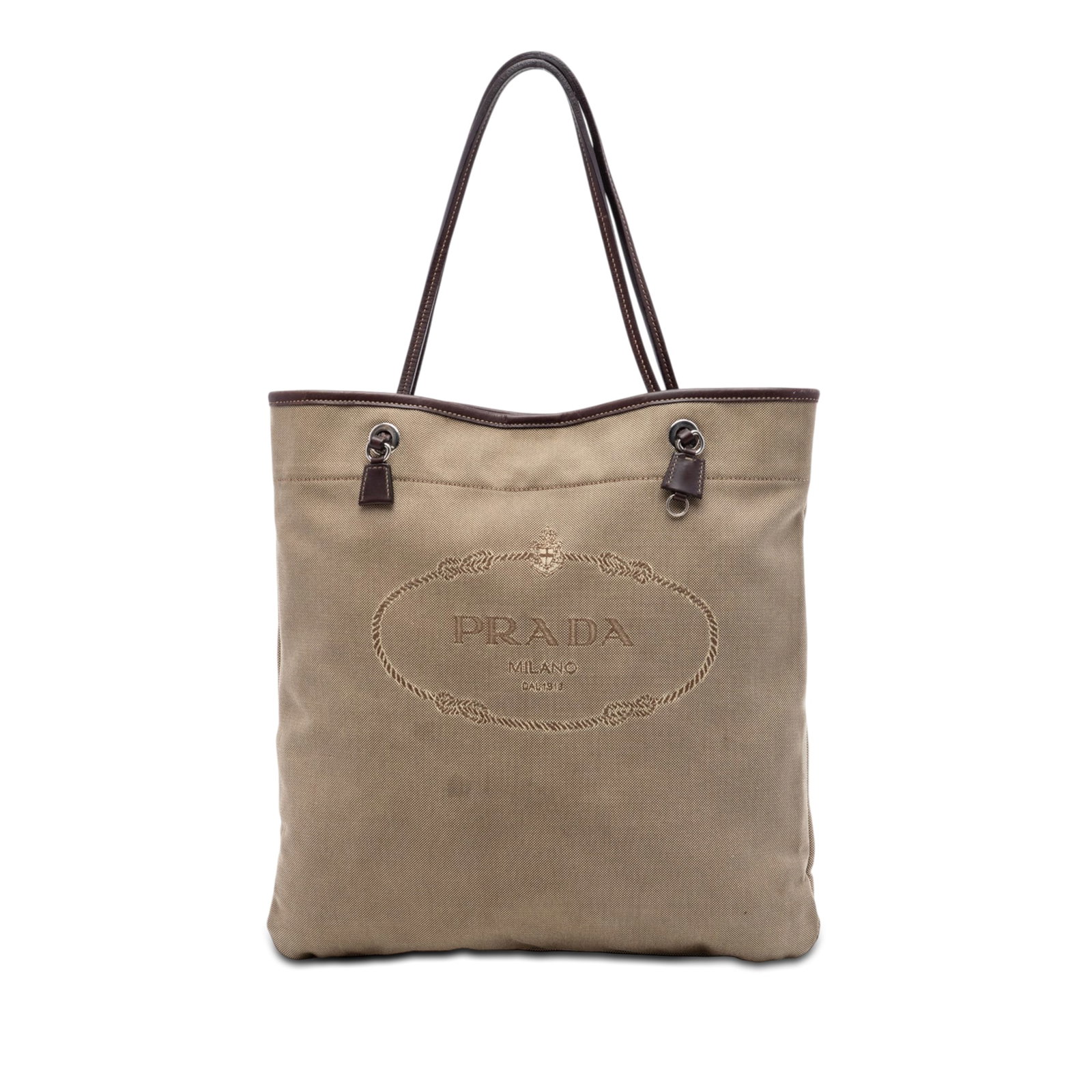 Prada Canapa Logo Canvas Tote Bag Brown: Prada Canapa Logo Canvas Tote Bag Brown Prada Canvas Canapa Logo Tote in brown fabric with leather trim and flat leather handles. The bag features an open top with magnetic snap closure, along with in
