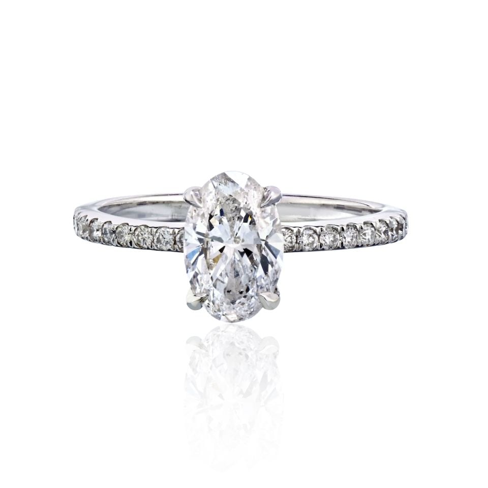 14K White Gold Engagement Ring with Oval and Round Diamonds: 14K White Gold Engagement Ring with Oval and Round Diamonds This pre-owned engagement ring features a 1.21 carat oval diamond with an E color and I1 clarity, mounted in a 14K white gold setting. The b