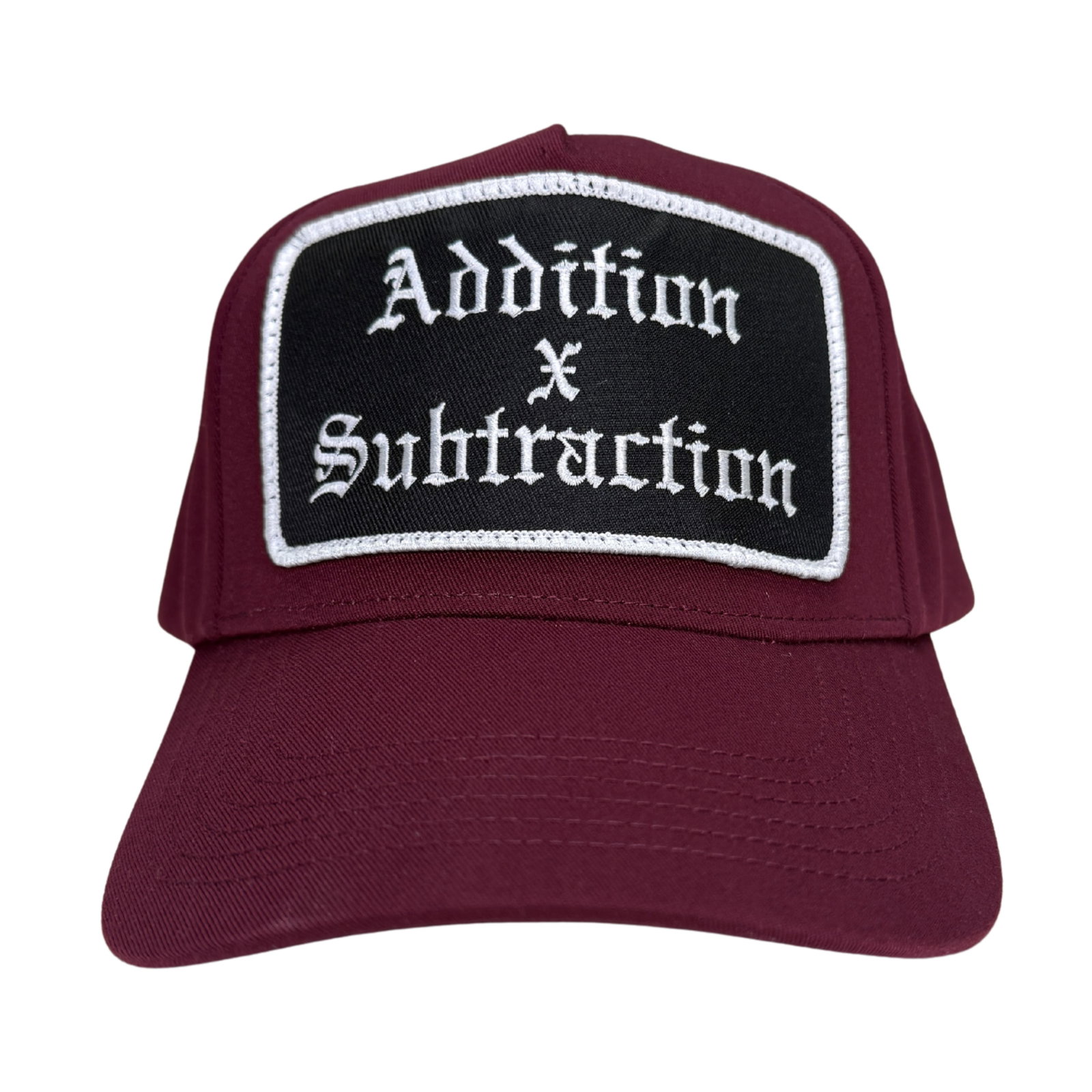 Burgundy Patch Hat Addition by Subtraction One Size: Burgundy Patch Hat Addition by Subtraction One Size This burgundy hat features a patch design with the 'Addition by Subtraction' motif. It is designed in a classic style and comes in a one size fits m