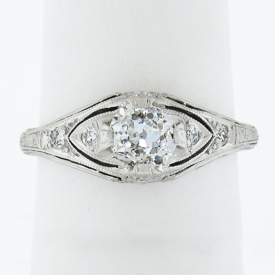 Edwardian Platinum Solitaire Diamond Ring with Milgrain Engraving: Edwardian Platinum Solitaire Diamond Ring with Milgrain Engraving This antique Edwardian engagement ring features a solid platinum band adorned with a total of seven natural diamonds. The centerpiece