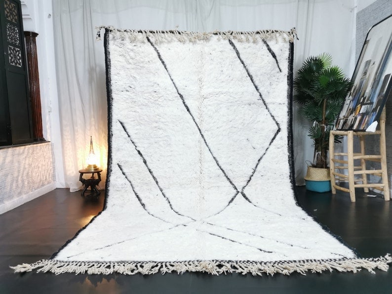 Handmade White Wool Rug with Black Engravings from Morocco: Handmade White Wool Rug with Black Engravings from Morocco Enhance your space with this stunning handmade white wool rug, featuring elegant black engraved lines. Crafted by skilled Berber women weaver