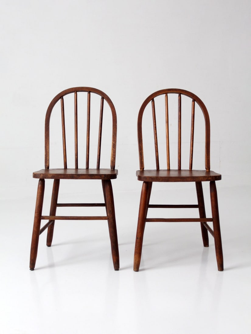 Vintage Windsor Style Spindle Back Chair Pair: Vintage Windsor Style Spindle Back Chair Pair This pair of vintage Windsor style chairs features classic spindle backs and shaped seats in a warm wood tone. With their simple, well-proportioned lines,