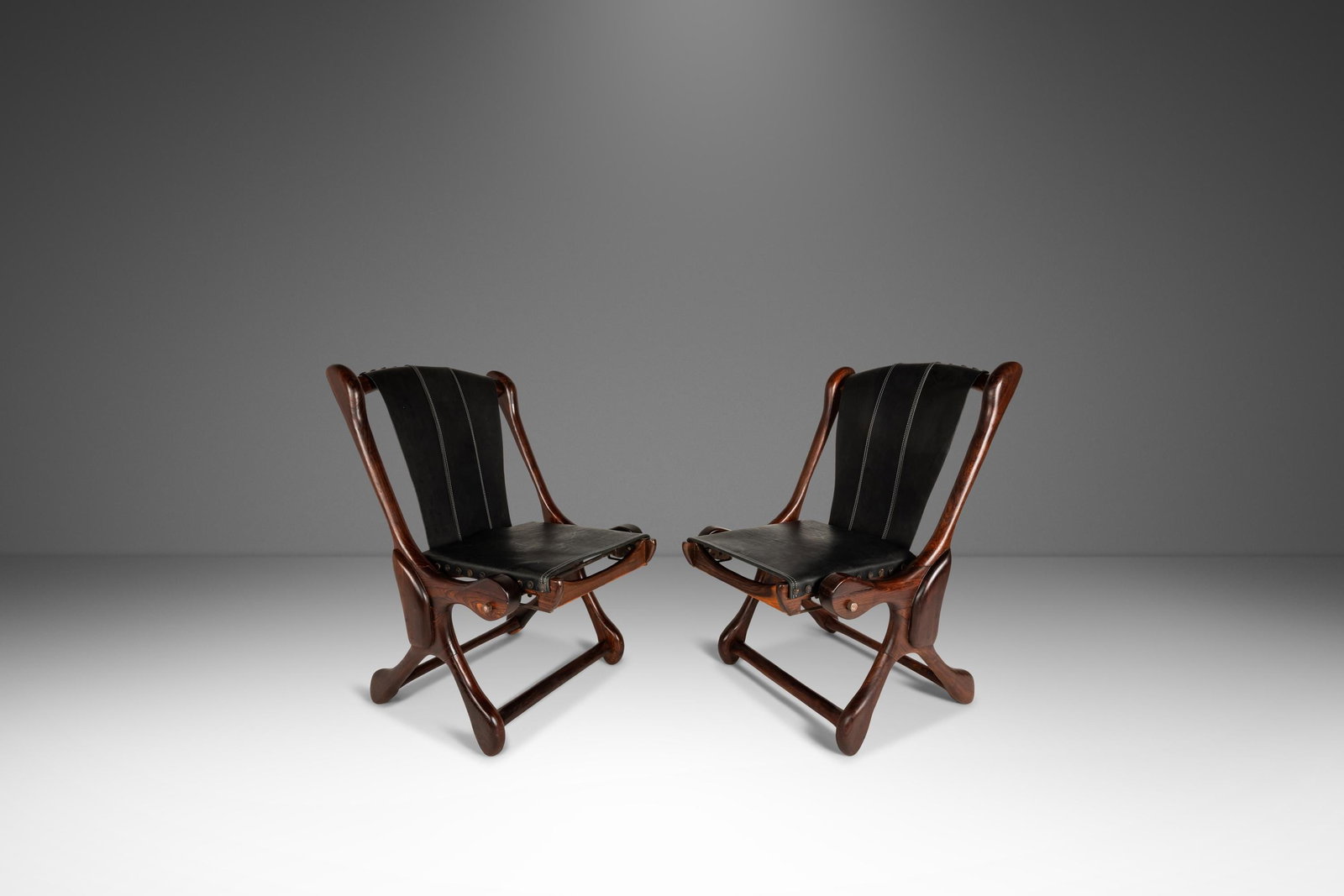 Pair of Shoemaker Sloucher Rosewood Leather Sling Chairs: Pair of Shoemaker Sloucher Rosewood Leather Sling Chairs This rare set includes two mid-century modern "Sloucher" sling chairs designed by Don S. Shoemaker for Senal Furniture in the 1960s. Crafted in