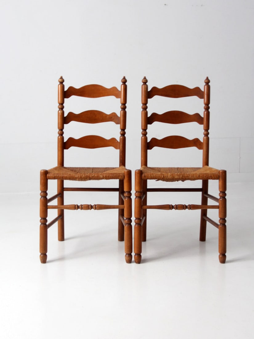 Pair of Antique Ladder Back Chairs with Rush Seats: Pair of Antique Ladder Back Chairs with Rush Seats Enhance your living space with this pair of antique ladder back chairs, showcasing classic French country charm. The elegantly designed ladder backs 