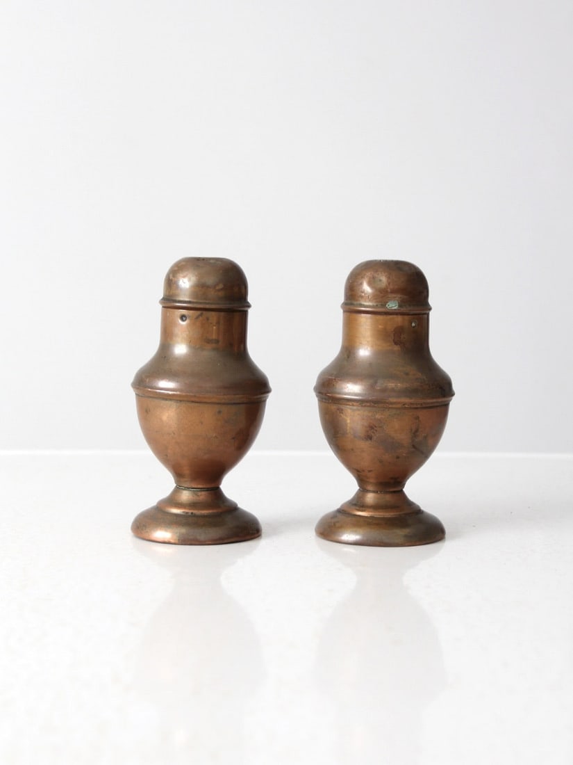 Pair of Classic Urn Shape Copper Salt and Pepper Shakers: Pair of Classic Urn Shape Copper Salt and Pepper Shakers This vintage set features copper salt and pepper shakers with a classic urn silhouette and pedestal base. The pierced tops add subtle detail to