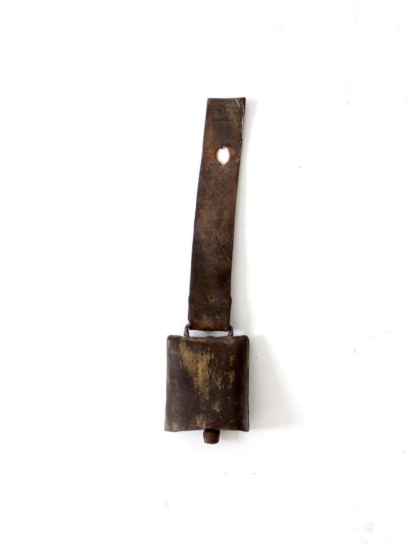 Rustic Antique Cow Bell with Leather Strap and Gold Finish: Rustic Antique Cow Bell with Leather Strap and Gold Finish This antique cow bell showcases a wide leather strap and remnants of its original gold finish, highlighting its rustic charm. The weathered p