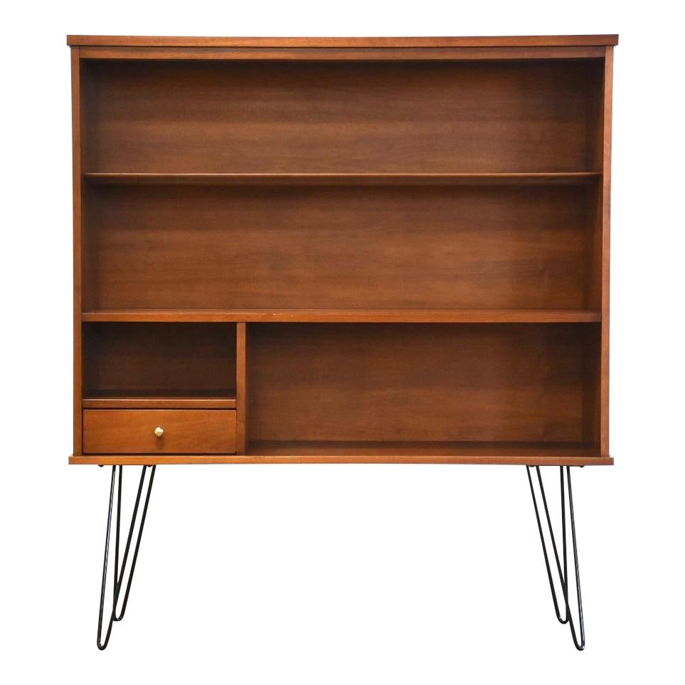 Mid Century Modern Walnut Bookcase with Chrome Accents: Mid Century Modern Walnut Bookcase with Chrome Accents This elegant mid-century modern bookcase features a rich walnut finish complemented by sleek black hairpin legs and a stylish chrome drawer pull.