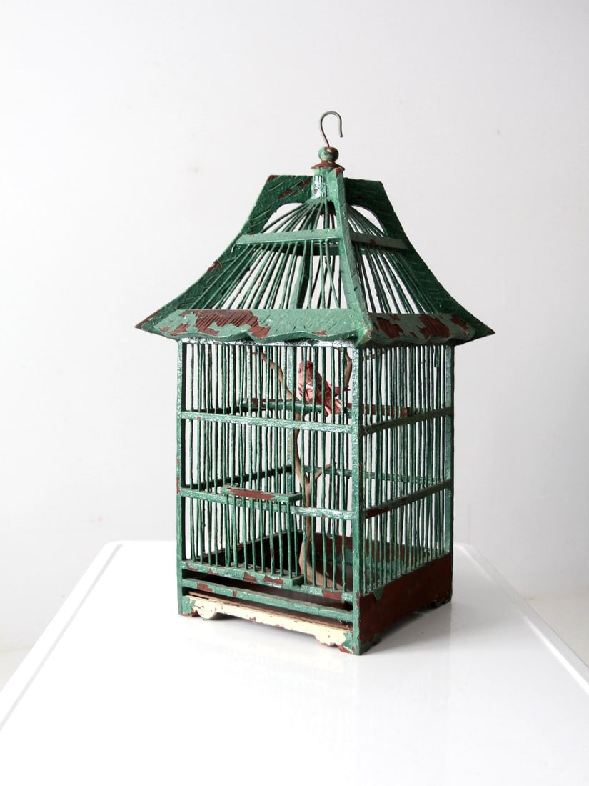 Charming Antique Wooden Bird Cage with Peaked Roof and Faux Bird: Charming Antique Wooden Bird Cage with Peaked Roof and Faux Bird This antique bird cage showcases a charming design with a peaked roof and a removable base. Crafted from painted wood, it features a sl