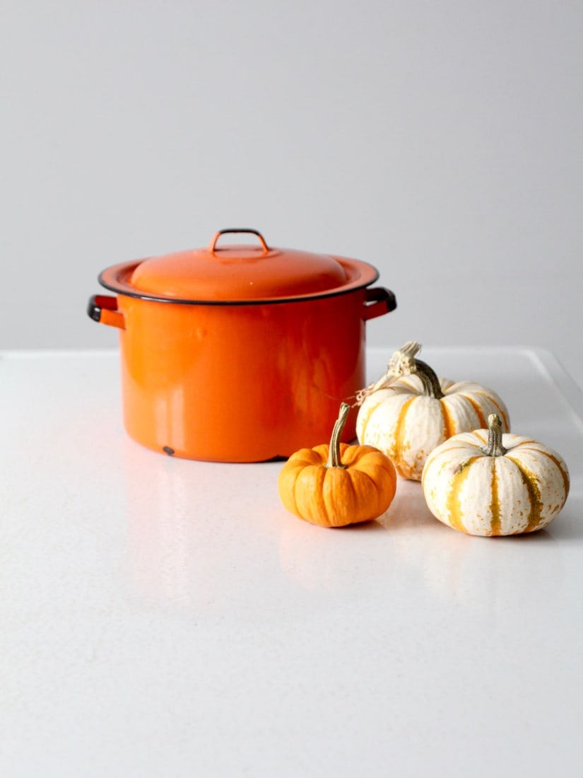 Vintage Mid-Century Orange Enamel Pot with Double Handles: Vintage Mid-Century Orange Enamel Pot with Double Handles This mid-century enamelware pot showcases a vibrant orange finish complemented by double handles and a stylish lid featuring black trim. The p
