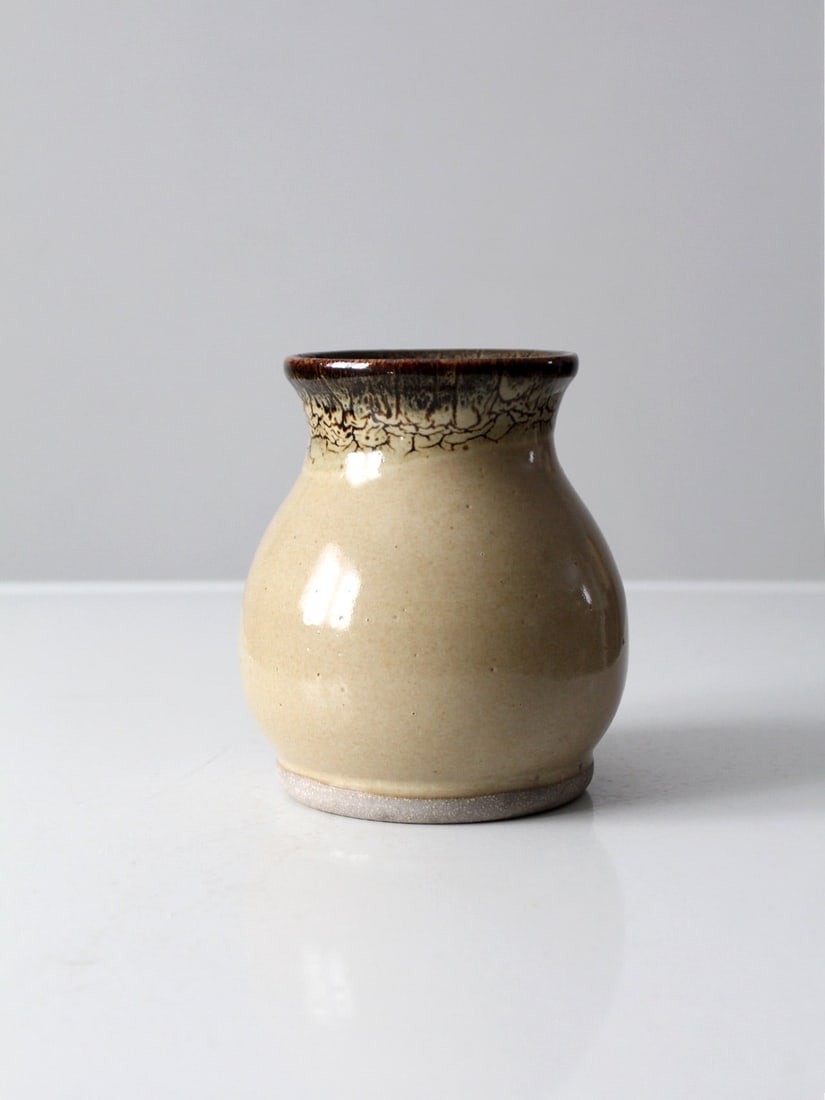 Signed Vintage Studio Pottery Vase Ecru Glaze 6.5 Inch: Signed Vintage Studio Pottery Vase Ecru Glaze 6.5 Inch This vintage studio pottery vase showcases exquisite craftsmanship, featuring a warm ecru glaze complemented by a crackled dark brown trim. The v