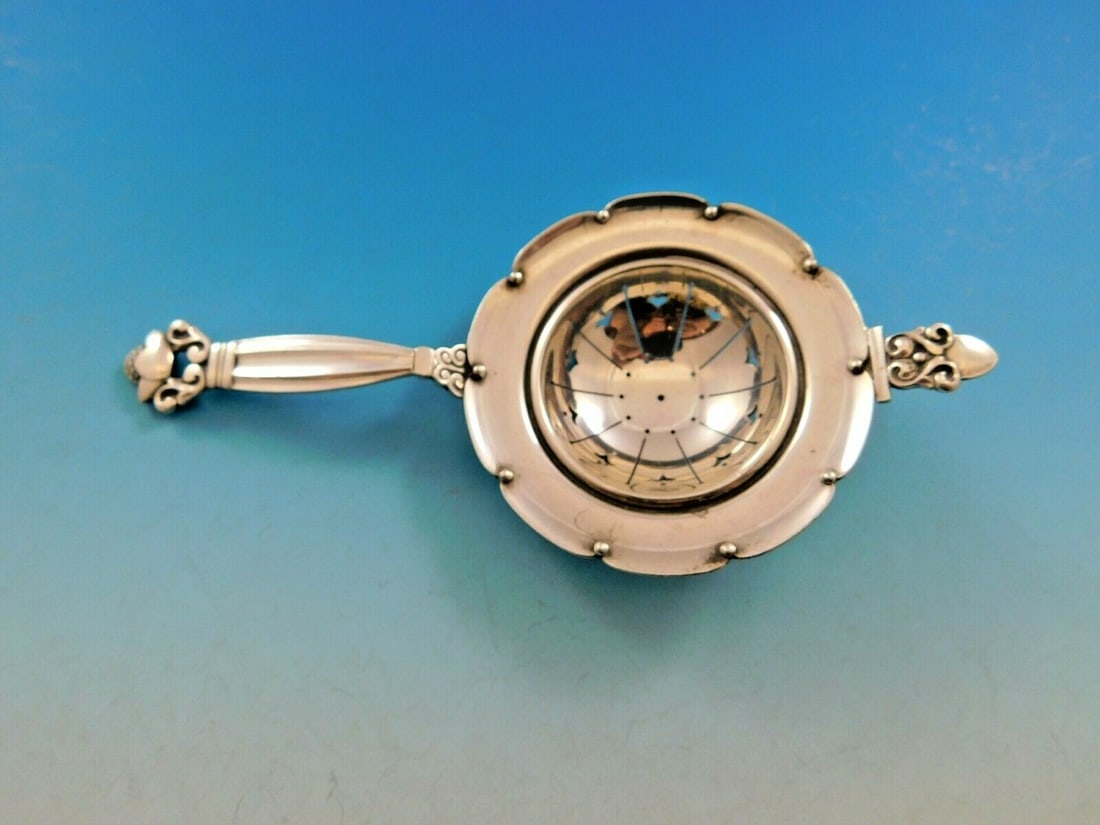 Georg Jensen Acorn Sterling Silver Tea Strainer with Rest 5 3/4": Georg Jensen Acorn Sterling Silver Tea Strainer with Rest 5 3/4" This exquisite tea strainer from Georg Jensen's Acorn pattern is crafted in sterling silver and measures 5 3/4". Designed with a natura