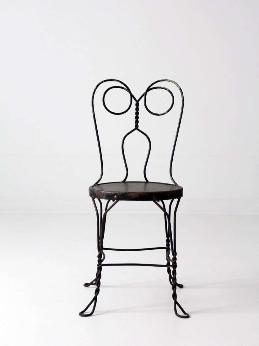 Charming Vintage Black Metal Ice Cream Parlor Chair: Charming Vintage Black Metal Ice Cream Parlor Chair This vintage black ice cream parlor chair is a charming addition to any space. Crafted from sturdy metal, it features a classic 'spectacle' design b