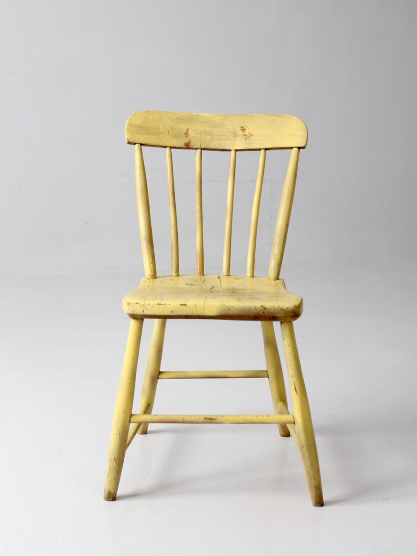 Early 20th Century Yellow Painted Primitive Chair: Early 20th Century Yellow Painted Primitive Chair This antique primitive plank seat chair from the early 20th century features a shaped wooden seat, tapered legs, and a simple spindle back beneath a c