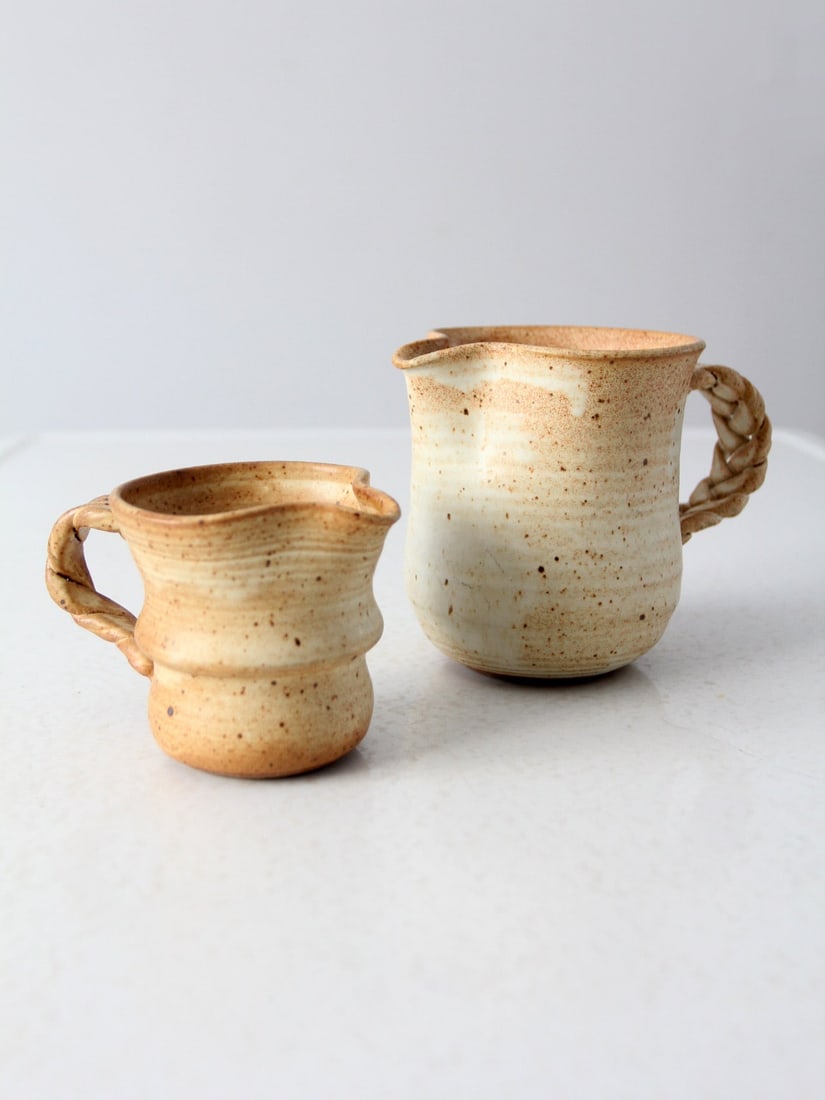 Signed Vintage Studio Pottery Pitchers Pair with Braided Handles: Signed Vintage Studio Pottery Pitchers Pair with Braided Handles This exquisite pair of vintage studio pottery pitchers showcases the artistry of handmade craftsmanship. Each pitcher features a unique