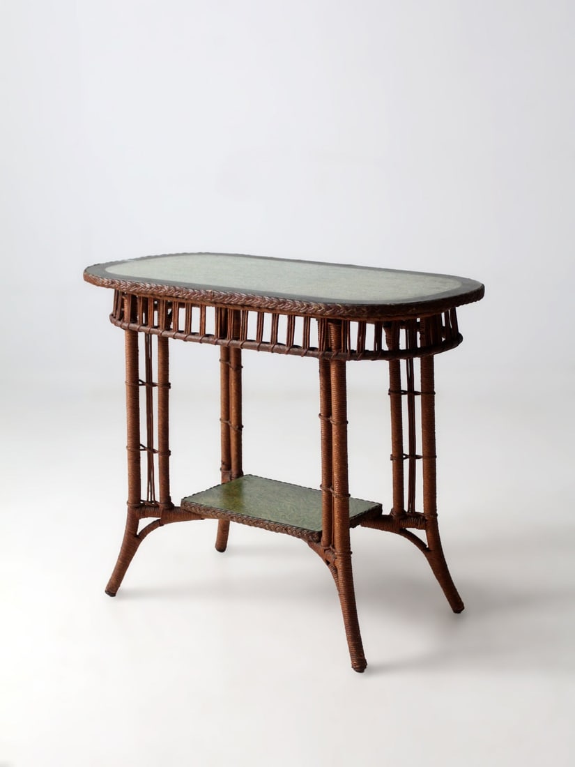 American Wicker Oval Top Console Table with Painted Panels Circa Early 1900s: American Wicker Oval Top Console Table with Painted Panels Circa Early 1900s This early 20th-century American wicker accent table features a long oval top and a lower shelf with painted inset panels. 