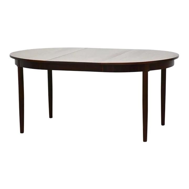 1960s Danish Modern Extending Oval Rosewood Dining Table: 1960s Danish Modern Extending Oval Rosewood Dining Table This stunning 1960s Danish Modern dining table showcases a beautiful rosewood finish. The table features a round shape that extends to an oval 