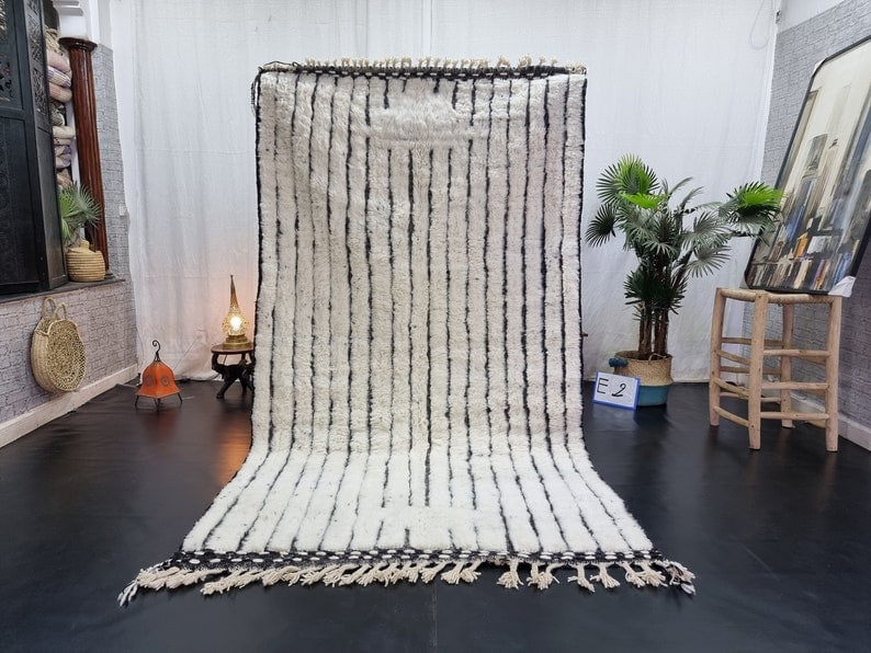 Handwoven Moroccan Berber Wool Rug 10 x 5 Feet: Handwoven Moroccan Berber Wool Rug 10 x 5 Feet This authentic white handmade Moroccan Berber wool rug features an exquisite engraved black pattern that enhances its visual appeal. Handwoven by local B