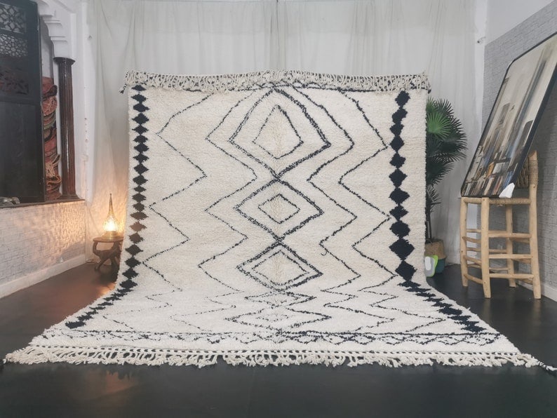 Handmade Moroccan Berber Wool Rug Soft White with Black Pattern: Handmade Moroccan Berber Wool Rug Soft White with Black Pattern Experience the elegance of the Soft White Handmade Moroccan Berber Wool Rug, featuring a captivating black pattern and lines. This rug i