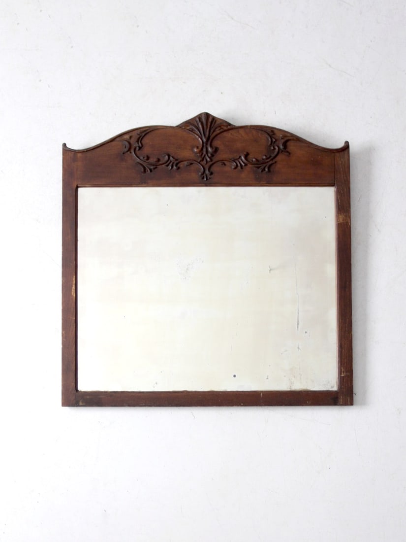 Antique Carved Wood Mirror with Beveled Glass Vintage Charm: Antique Carved Wood Mirror with Beveled Glass Vintage Charm This exquisite antique wall mirror showcases a beautifully carved wooden frame with an ornate crest, making it a stunning addition to any sp