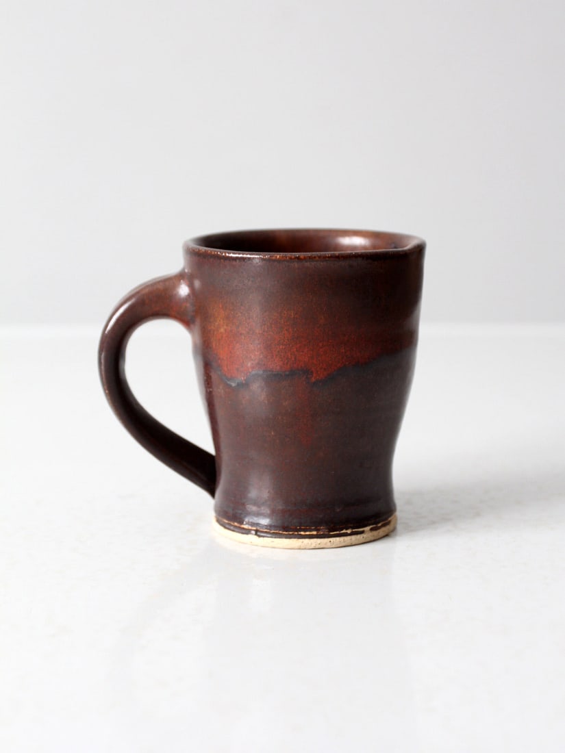 Handcrafted Vintage Studio Pottery Mug Maroon Ochre Glaze: Handcrafted Vintage Studio Pottery Mug Maroon Ochre Glaze This vintage studio pottery mug showcases a beautifully hand-thrown form adorned with a unique maroon and ochre glaze. It is both functional a