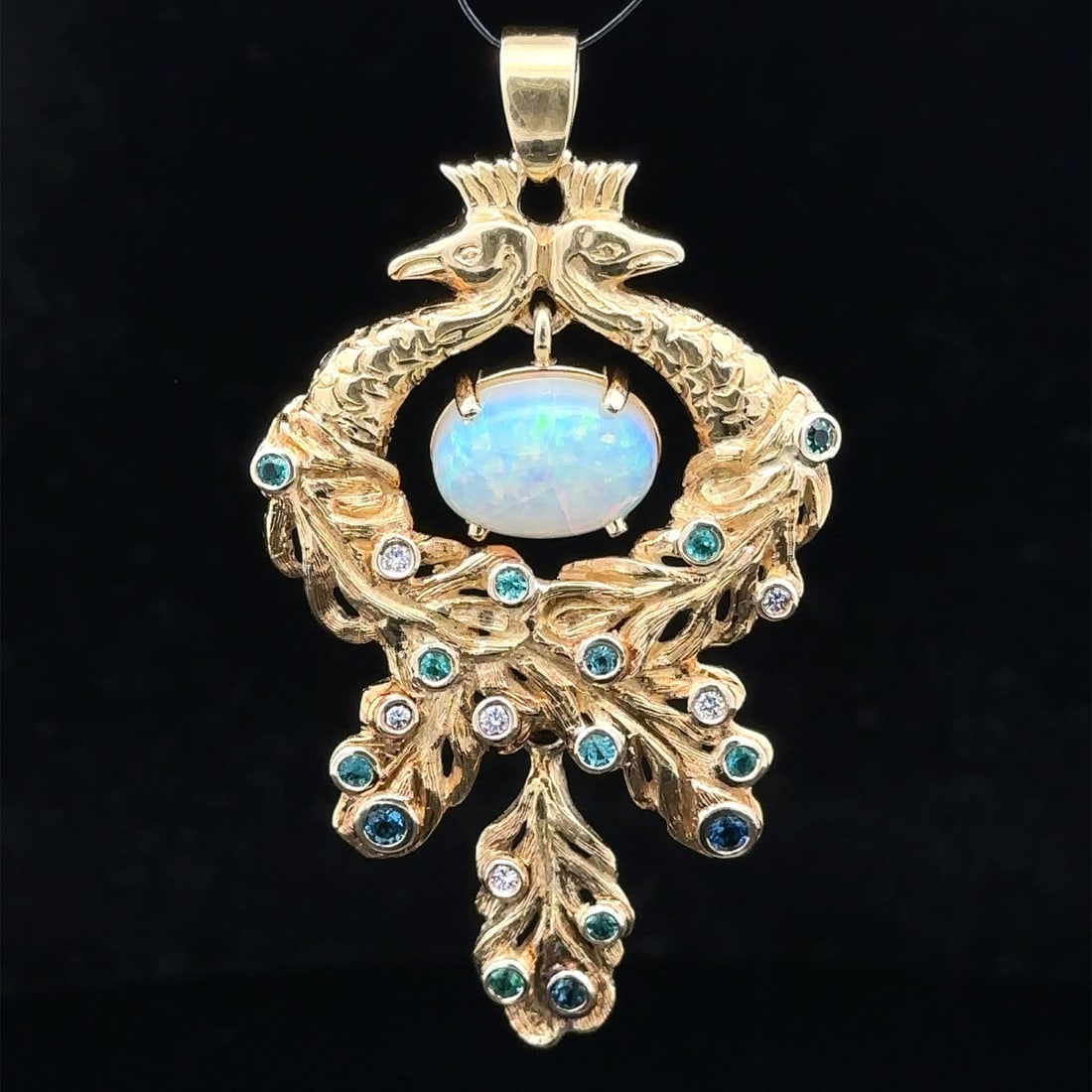 Australian Opal Diamond Paraiba Tourmaline Peacock Pendant in 18k Yellow Gold: Australian Opal Diamond Paraiba Tourmaline Peacock Pendant in 18k Yellow Gold This pendant features a dual peacock design crafted in solid 18k yellow gold. At its center is a natural Australian opal i