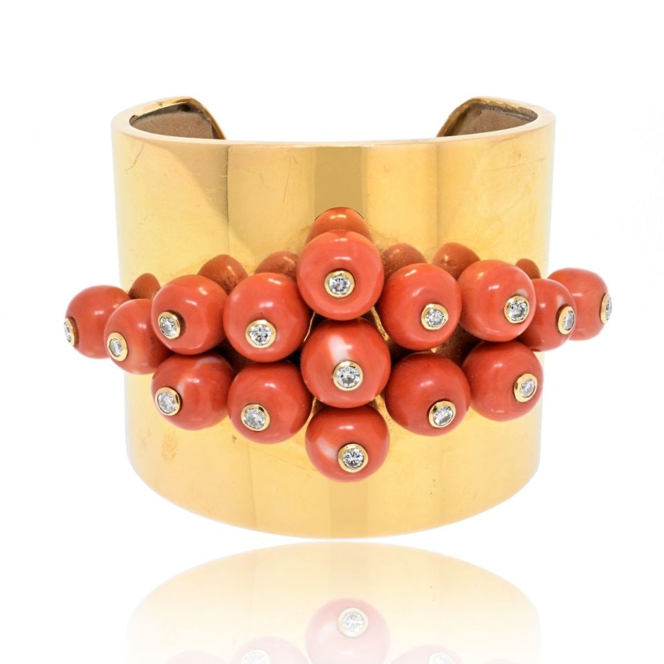 1960s 18K Yellow Gold Coral Diamond Cuff Bangle Bracelet: 1960s 18K Yellow Gold Coral Diamond Cuff Bangle Bracelet This stunning cuff bangle bracelet, dating back to the 1960s, is crafted from luxurious 18K yellow gold. The bracelet features a vibrant coral 