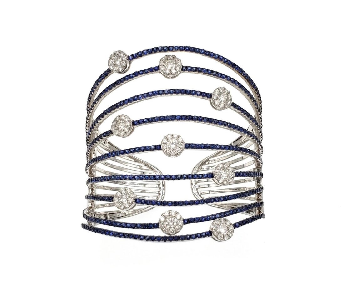 Elegant 14.10ct Blue Sapphire Diamond Cuff Bracelet in 18k White Gold: Elegant 14.10ct Blue Sapphire Diamond Cuff Bracelet in 18k White Gold This stunning cuff bracelet is a remarkable blend of elegance and style, crafted from 18k white gold. Featuring a unique design wi