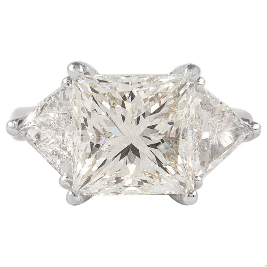 6.05ct GIA Emerald Cut Diamond 3-Stone Platinum Ring: 6.05ct GIA Emerald Cut Diamond 3-Stone Platinum Ring This exquisite three-stone engagement ring features a stunning 6.05 ct emerald cut diamond at its center, accompanied by two trilliant cut diamonds