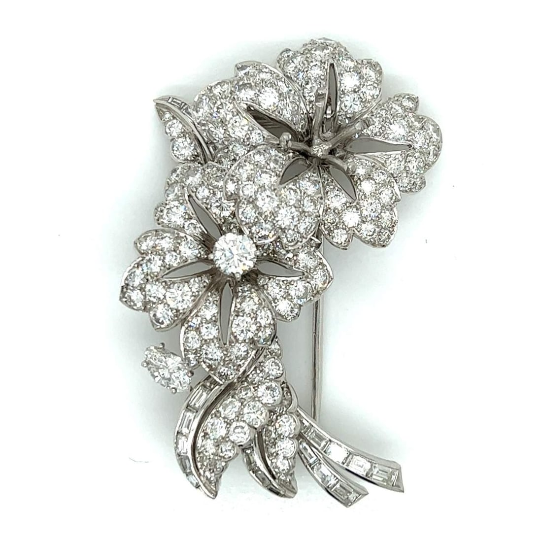 Platinum Art Deco Brooch with 8.40 Carat Diamonds and Emerald Accent: Platinum Art Deco Brooch with 8.40 Carat Diamonds and Emerald Accent This Art Deco brooch is crafted in platinum and features an elegant flower design. It is set with approximately 1.50 carats of Colo