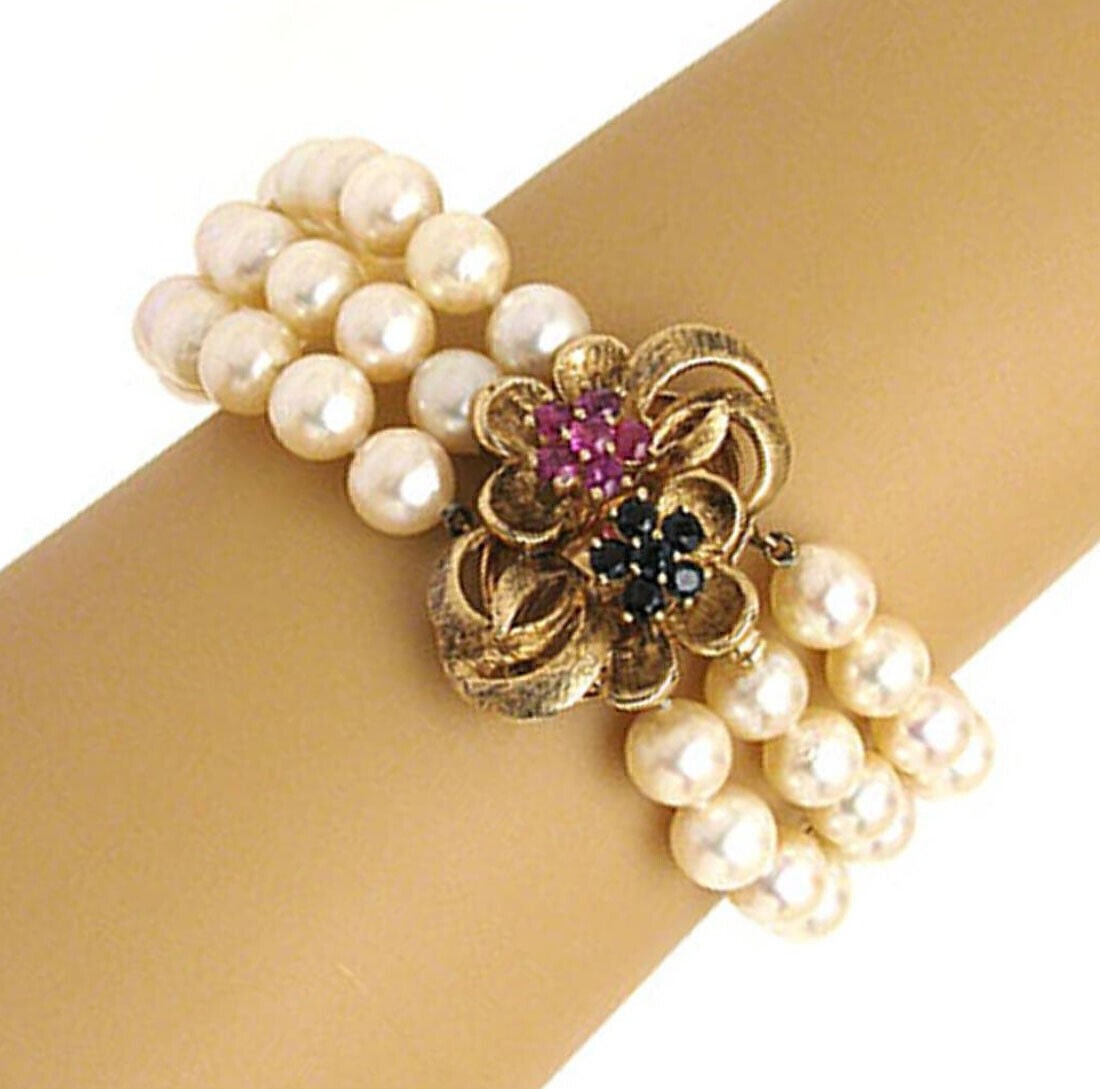 Vintage 14k Yellow Gold Cultured Pearl Bracelet with Ruby Sapphire Floral Clasp: Vintage 14k Yellow Gold Cultured Pearl Bracelet with Ruby Sapphire Floral Clasp Vintage triple-strand cultured pearl bracelet in solid 14k yellow gold with a floral clasp accented by sapphires and rub