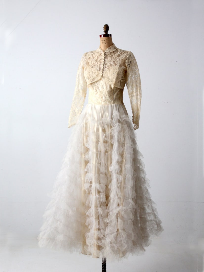 Charming Vintage Two-Piece Lace Wedding Dress with Crop Jacket: Charming Vintage Two-Piece Lace Wedding Dress with Crop Jacket This vintage wedding gown is a stunning two-piece ensemble, perfect for a romantic and nostalgic bridal look. The gown features a fitted 