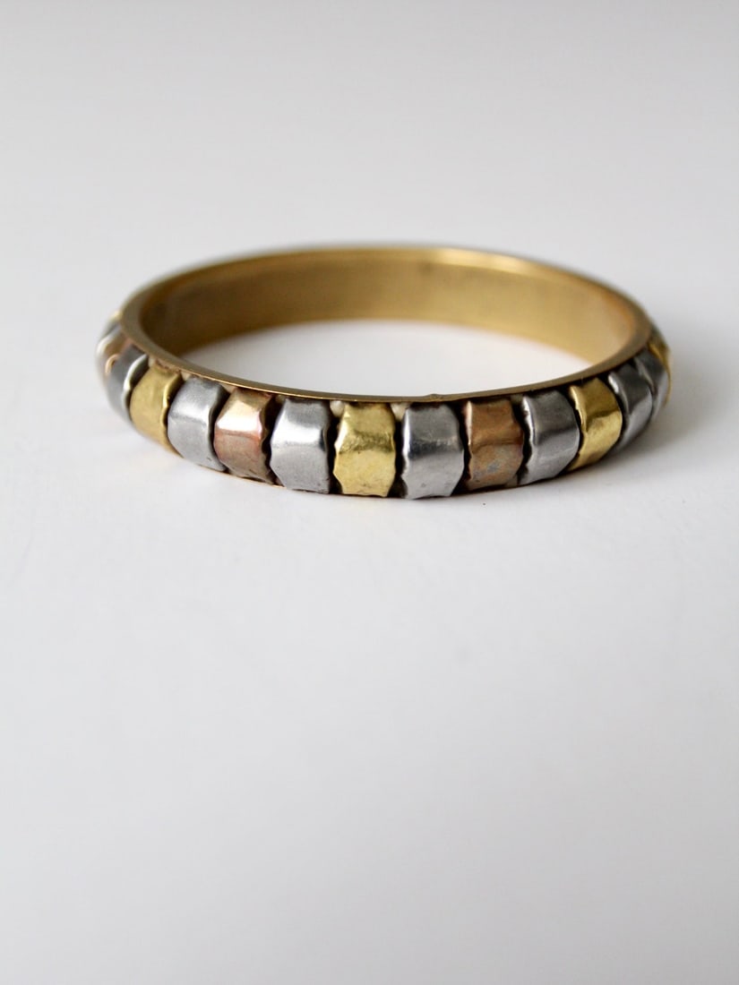 Vintage Three Tone Mixed Metal Bangle with Brass Interior: Vintage Three Tone Mixed Metal Bangle with Brass Interior This vintage mixed metal bangle showcases a unique design with a brass interior band complemented by square insets in copper, silver, and bras