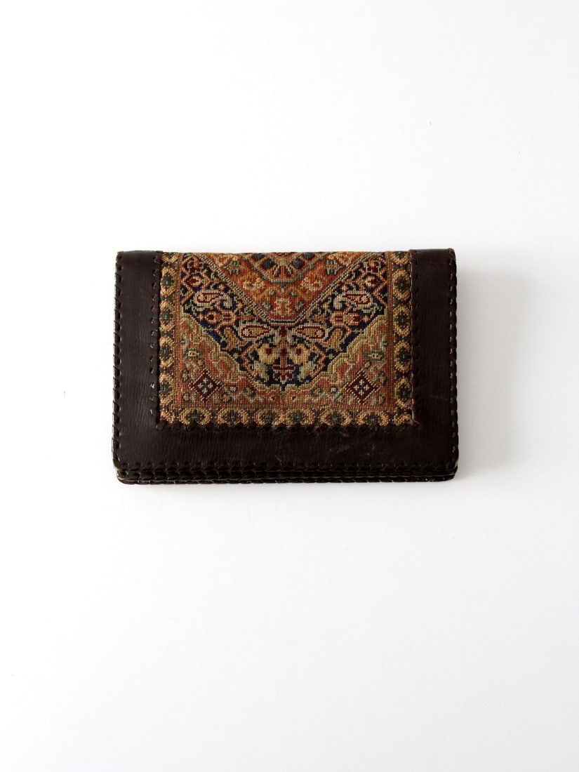 Vintage Leather Wallet with Tapestry Panel Snap Closure: Vintage Leather Wallet with Tapestry Panel Snap Closure This vintage leather wallet features a stunning tapestry-paneled front, adding a unique touch to its design. Crafted from dark brown leather, it