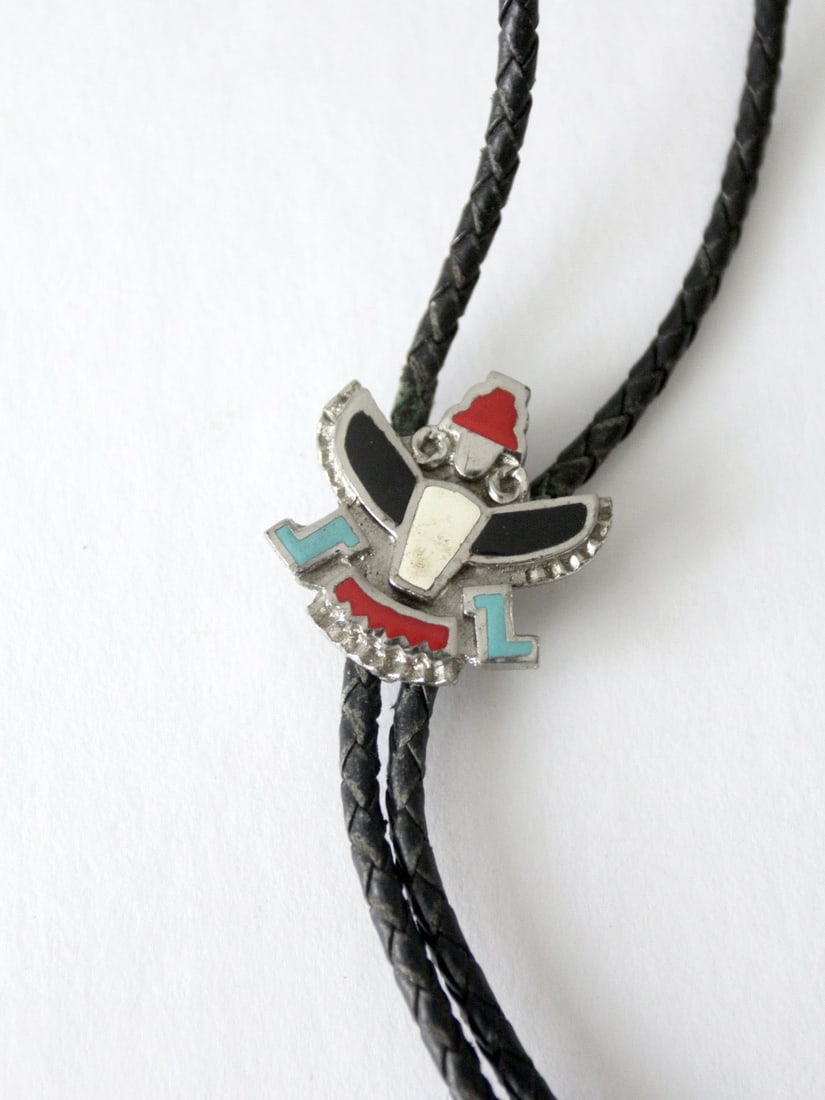 Vintage Zuni Knife-Wing Bolo Tie with Black Leather Cord: Vintage Zuni Knife-Wing Bolo Tie with Black Leather Cord Embrace the essence of classic Southwestern style with this Vintage Southwestern Knife-Wing Bolo Tie. It features a striking Zuni Knife-Wing wa